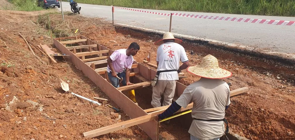 Crew forming a lined roadside drain